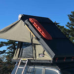Bush Company AX27 Clamshell Rooftop Tent attached to a vehicle with trees in the background