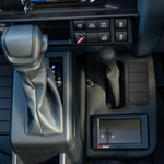 Close-up of a car's gear shift and dashboard controls.