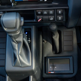 Close-up of a car's gear shift and dashboard controls.