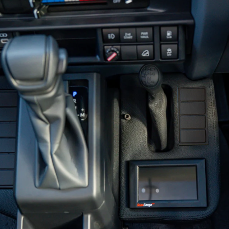 Close-up of a car's gear shift and dashboard controls.