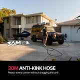 Person using a long hose to clean a vehicle in front of a house