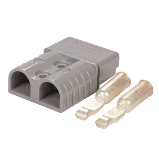 Grey Anderson SB50 connector housing at an angle with two silver contacts laid beside it, the Anderson Power Products name moulded into the top face and the plus and minus polarity marks on the body