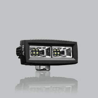 ALTIQ CX4 scene work light at a three-quarter angle, the wide rectangular lens holding two reflector segments each with a cluster of LEDs, the ALTIQ name on the end cheek and the mounting bracket below