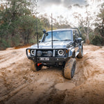 Off-road vehicle driving on a muddy path with trees in the background