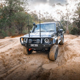 Off-road vehicle driving on a muddy path with trees in the background