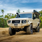 sandy Toyota off-road vehicle on a dirt road with trees in the background