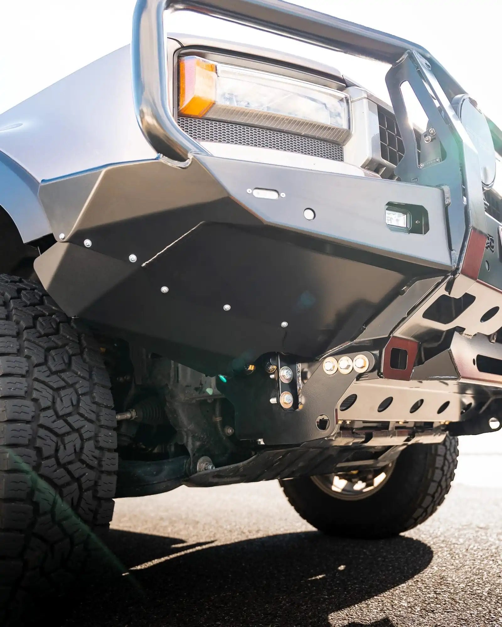 Close-up of a vehicle's front bumper and tire on a road