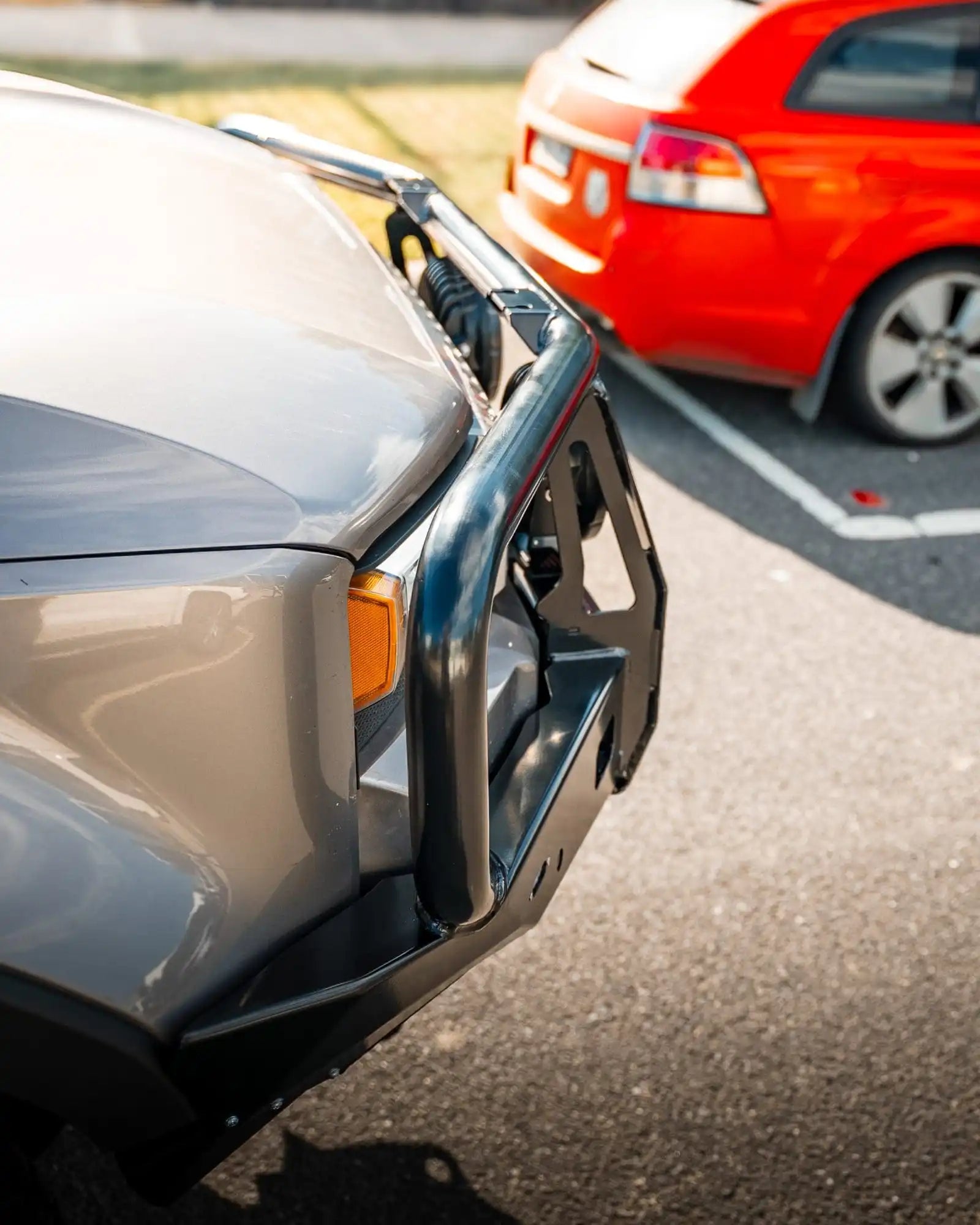 Close-up of a car bumper with another car partially visible in the background.