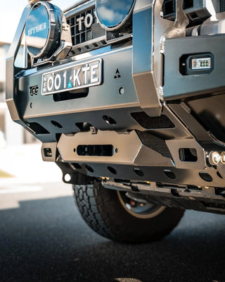 Close-up of a vehicle's front bumper with visible branding and license plate.