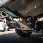 Close-up of a vehicle's undercarriage with visible suspension components on a road.