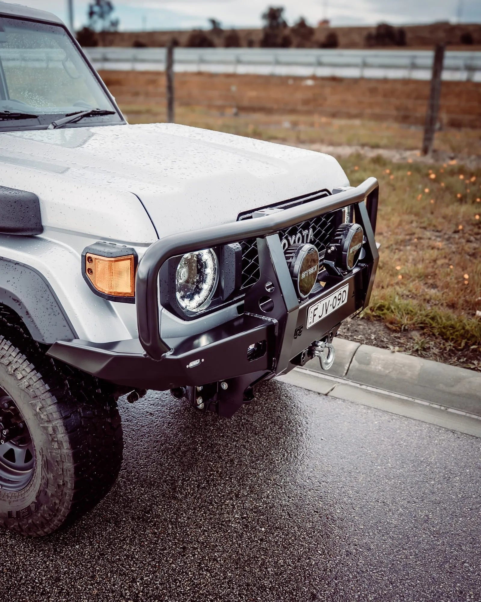 White off-road vehicle on a road with a rural landscape in the background