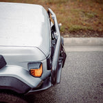 Close-up of a vehicle's front bumper and headlight on a road.