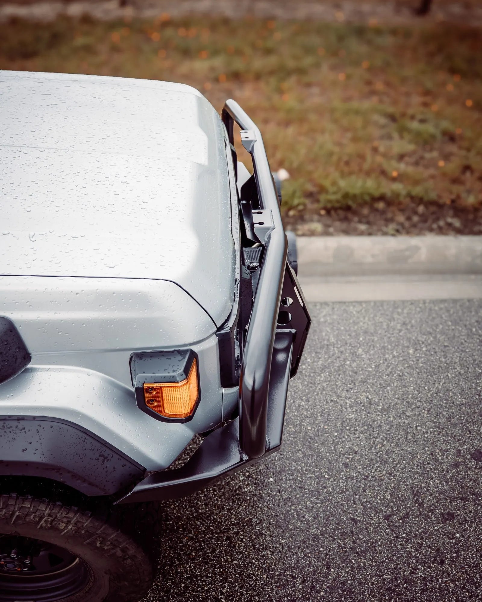 Close-up of a vehicle's front bumper and headlight on a road.