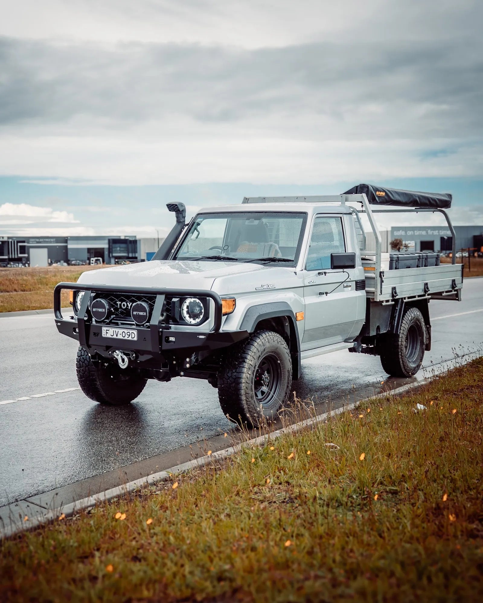 White Toyota truck on a wet road with a cloudy sky