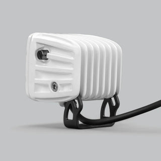 White DX4 Scene work light seen from the side, the ribbed white housing with its adjustment screw and the black mounting bracket with the lead running behind