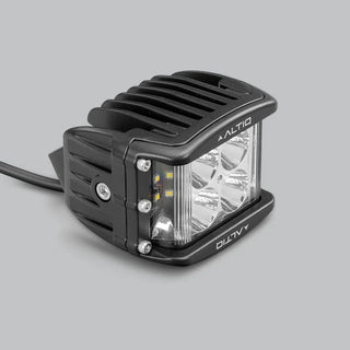 DX4 hybrid work light at a three-quarter angle, showing the round spot optics and the side flood strip together behind the clear lens