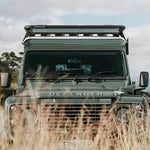 Land Rover Defender in a grassy field with a clear sky
