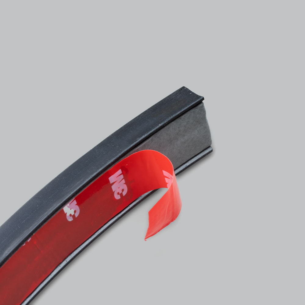 End of the wire concealer with the red 3M adhesive backing tape partly peeled away from the underside of the black moulded channel