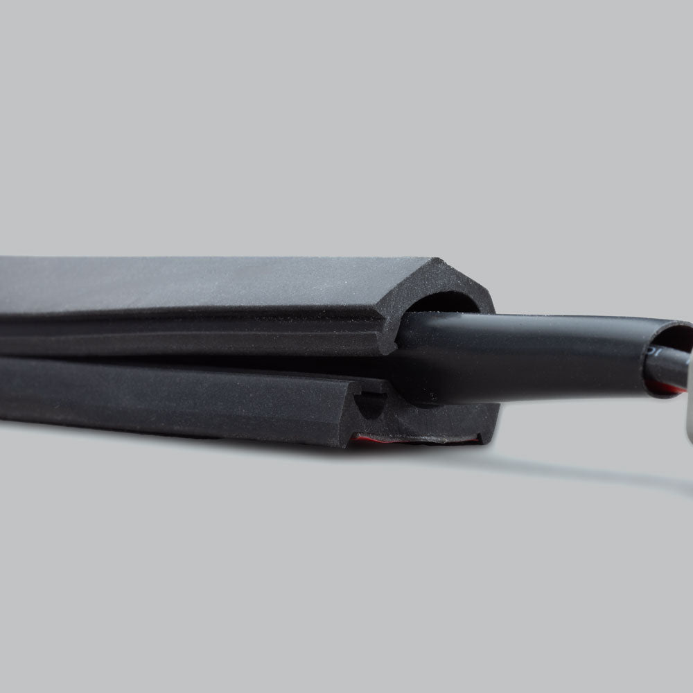 Cut end of the wire concealer, showing the internal round channel that holds the cable and the adhesive strip along the flat base