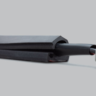 Cut end of the wire concealer, showing the internal round channel that holds the cable and the adhesive strip along the flat base