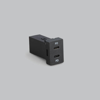 Toyota-fit dual USB-C charger at an angle, showing the depth of the body behind the panel and the two USB-C ports marked PD on the face