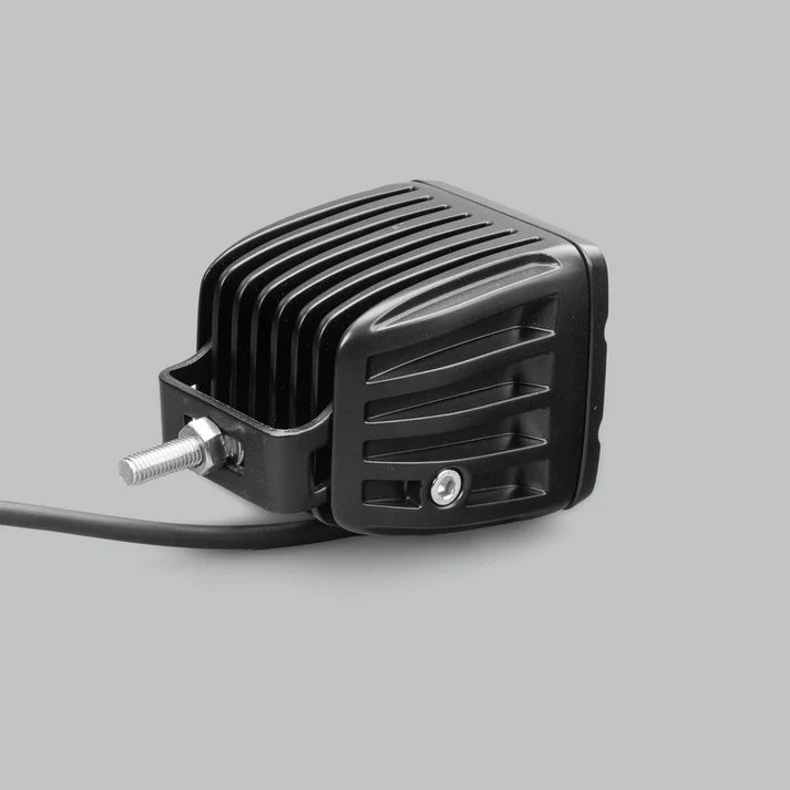 DX4 work light from above and to the side, showing the deeply finned cast heatsink, the stainless mounting bracket and threaded stud, and the lead leaving the rear
