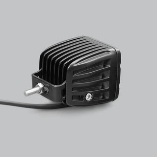 DX4 work light from above and to the side, showing the deeply finned cast heatsink, the stainless mounting bracket and threaded stud, and the lead leaving the rear