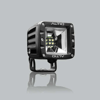 Black DX4 Scene work light at a three-quarter angle, the ALTIQ name on the bezel above a square reflector with nine LEDs, mounted on its black bracket