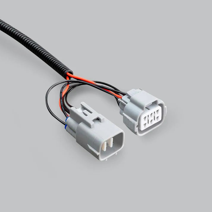 Close-up of the adaptor's two grey connectors, the male pins of one and the six-cavity face of the other, with the red and black tails running back into the sleeve