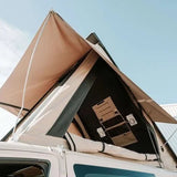 Car with an extended rooftop tent against a clear sky