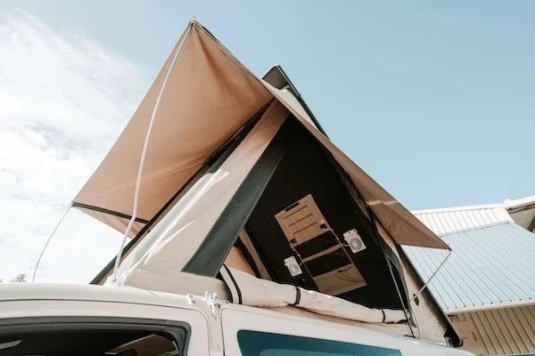 Car with an extended rooftop tent against a clear sky