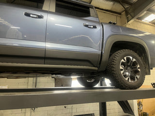 Gray SUV on a lift in a garage