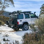 4x4 vehicle on a snowy road with trees and mountains in the background