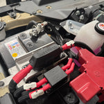 Close-up of a battery connection with red and black cables on a mechanical component.