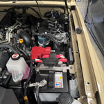 Open car hood revealing engine and battery components.