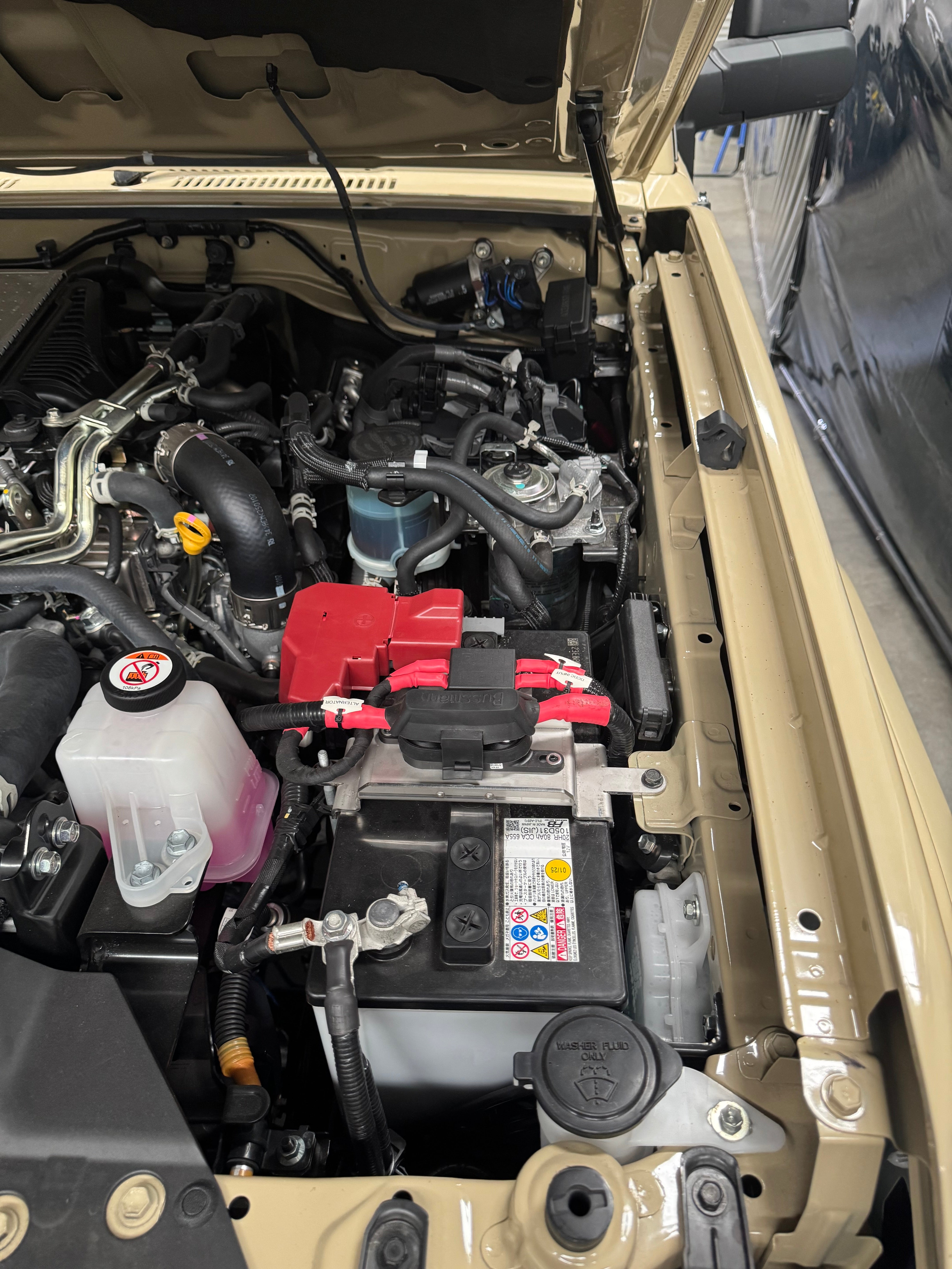 Open car hood revealing engine and battery components.