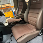 Beige car seat with visible Scheelmann branding in a workshop setting