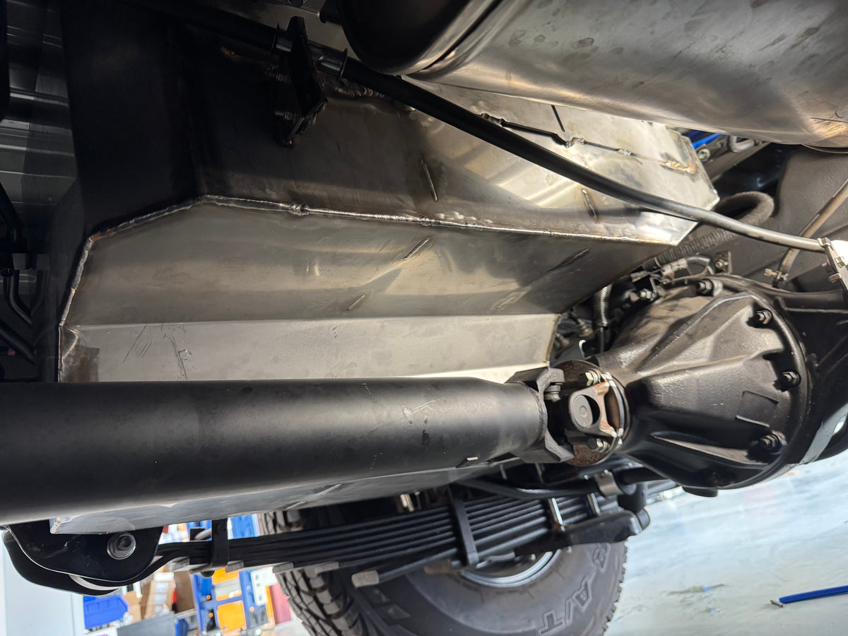 Close-up of a vehicle's undercarriage with suspension components & water tank.