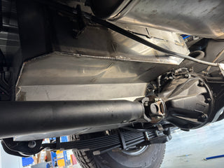 Close-up of a vehicle's undercarriage with suspension components & water tank.