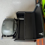 Gray and black grill on a white surface with a colorful object partially visible