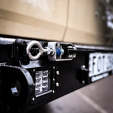 Close-up of a vehicle's license plate and light system with a blurred background.