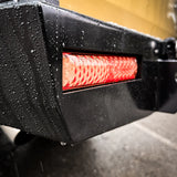 Close-up of a black vehicle bumper with a red LED light