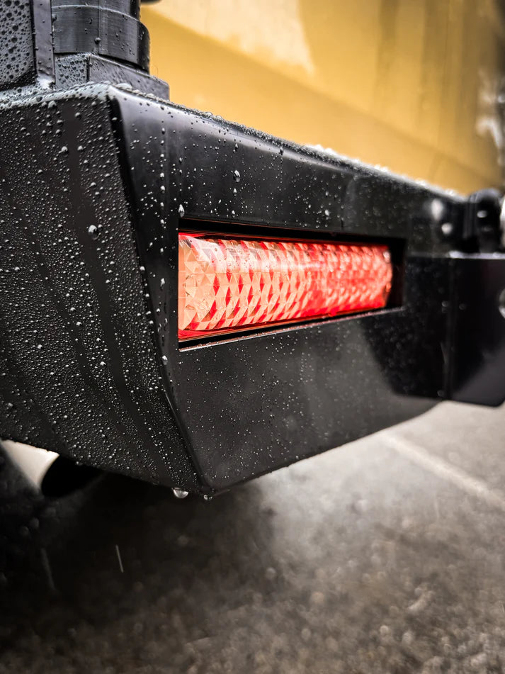 Close-up of a black vehicle bumper with a red LED light