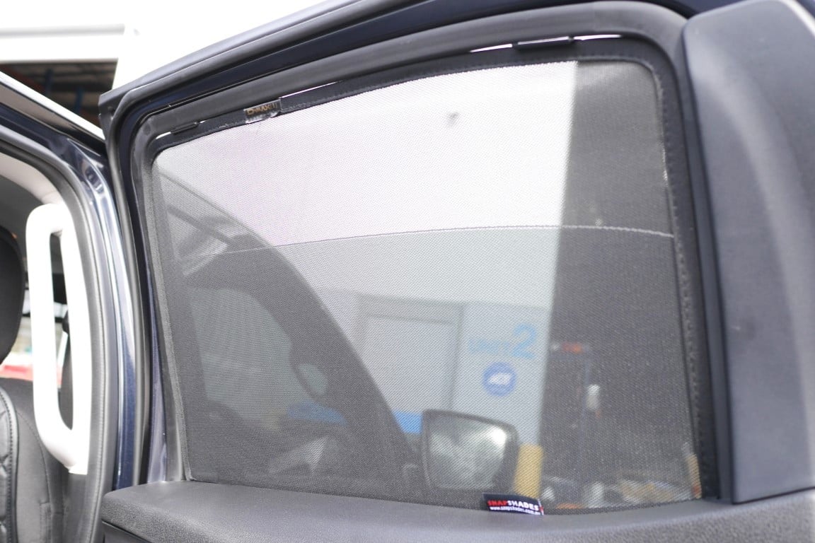 Car window with a sunshade covering it, showing reflection of a building.