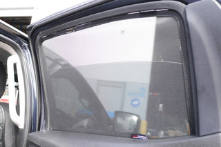 Car window with a sunshade covering it, showing reflection of a building.