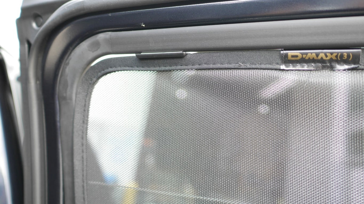 Car window with a mesh screen and 'D-MAX' branding on a vehicle door.