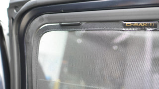 Car window with a mesh screen and 'D-MAX' branding on a vehicle door.