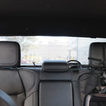 Backseat of a car with headrests and seat belts, showing a blurred outdoor background.