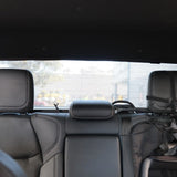 Backseat of a car with headrests and seat belts, showing a blurred outdoor background.