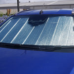 Blue car with a sunshade covering the windshield, parked outdoors.